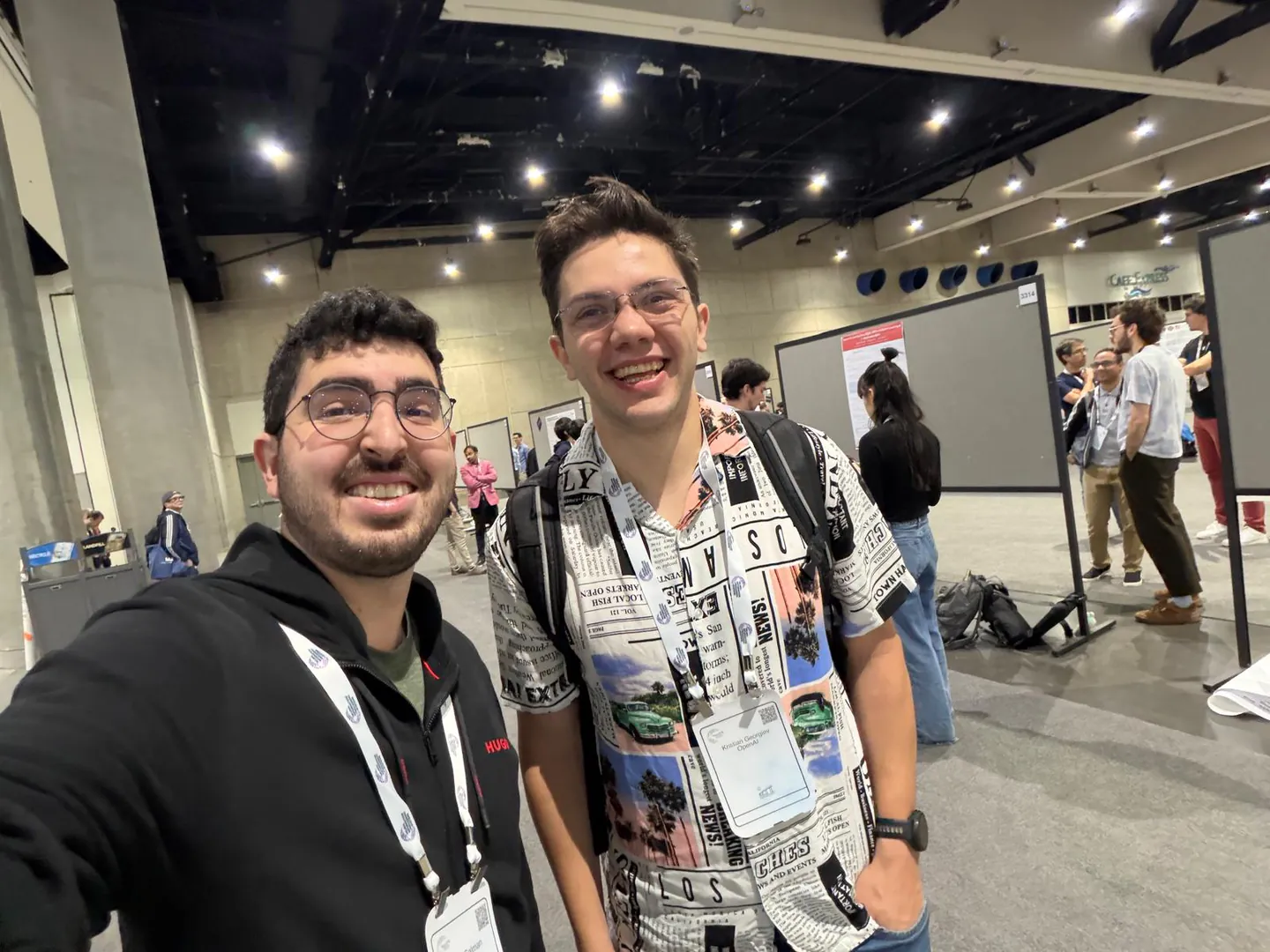 Hadi Salman takes a selfie with another smiling attendee in the NeurIPS poster hall